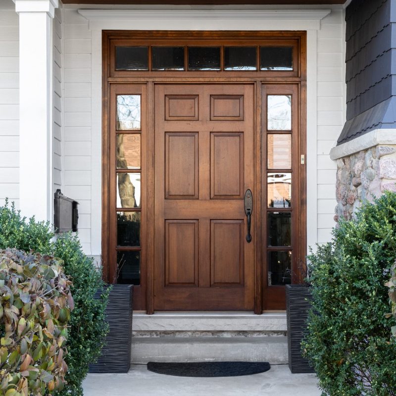 A modern mansion entrance speaks of sophistication with a beautiful wooden front door.